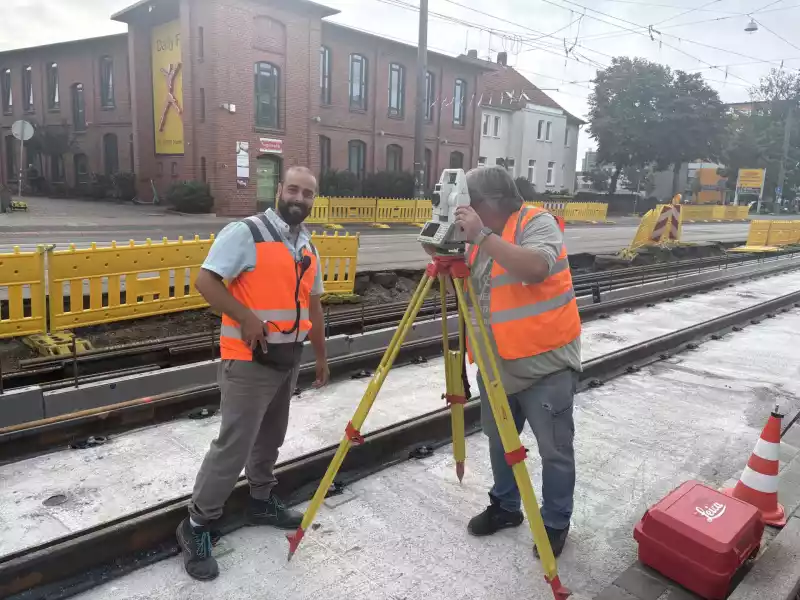 Zwei Vermesser der TransTecBau beim präzisen Einmessen von Gleisen auf einer Baustelle in Hannover